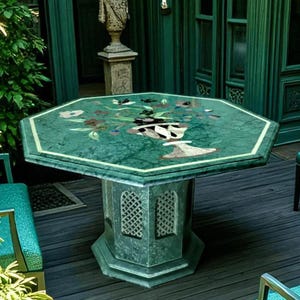May include: A green marble table and chairs set on a patio. The octagonal table, with a decorative inlaid design, is supported by a pedestal base. The chairs have dark metal frames and teal fabric seats. The table is approximately 1.2 meters in diameter.