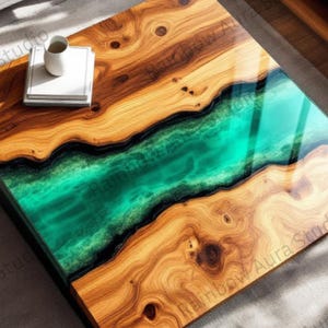 May include: A square wooden coffee table with a river of teal epoxy resin running through the center. The wood has a natural grain pattern with warm brown tones. A small stack of books and a mug sit on top.