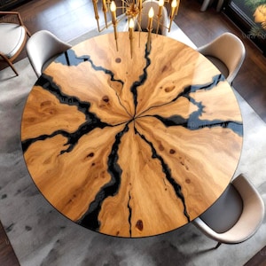 Puede incluir: Una mesa de comedor redonda de madera con un diseño único. La mesa presenta una veta de madera marrón claro con detalles de resina negra. Cuatro sillas rodean la mesa y una lámpara de araña cuelga encima. La mesa tiene unos 152 cm de diámetro.