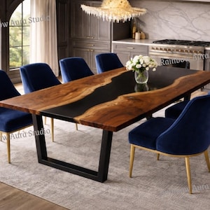 Op de afbeelding: Een moderne eettafel met een houten blad met een natuurlijke rand en een zwarte epoxyhars rivier. De tafel wordt ondersteund door een zwart metalen onderstel en is omringd door zes marineblauwe fluwelen stoelen met gouden poten.