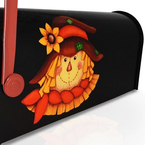 May include: A black mailbox with a painted scarecrow design. The scarecrow has a brown hat, a yellow face, and a red and orange scarf.