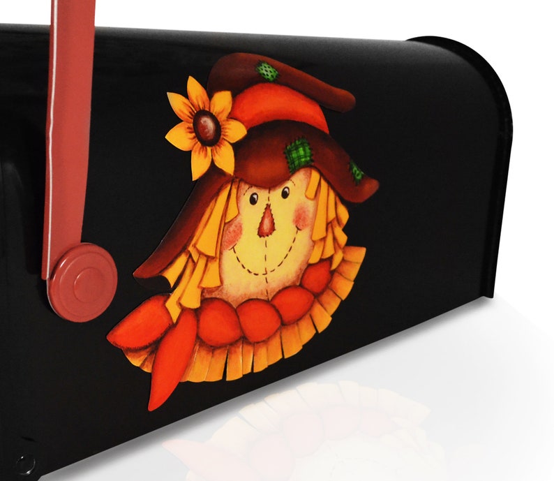 May include: A black mailbox with a painted scarecrow design. The scarecrow has a brown hat, a yellow face, and a red and orange scarf.