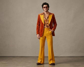 May include: A burnt orange velvet blazer with wide lapels worn over a floral patterned button-down shirt and mustard yellow flared trousers. The outfit includes large tinted sunglasses and a simple metallic pendant necklace.