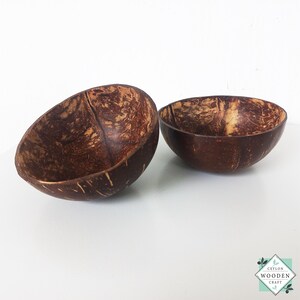 Puede incluir: Dos cuencos de coco hechos a mano con un acabado marrón natural. Los cuencos tienen un interior liso y un exterior texturizado, mostrando los patrones naturales de la cáscara de coco. Ideales para servir alimentos o como piezas decorativas.