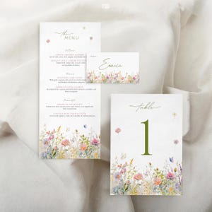 May include: A set of wedding stationery featuring a menu, place card, and table number. The designs have a white background with a floral border of pink, purple, and yellow flowers. The table number card has a large green number 1.