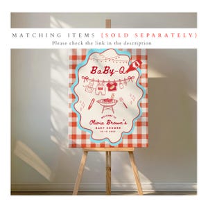 May include: A wooden easel displays a Baby-Q baby shower sign. The sign features a red and white checkered background with a blue scalloped border. The sign reads "Baby-Q" and "Welcome to Olivia Brown's Baby Shower 10.12.2024."