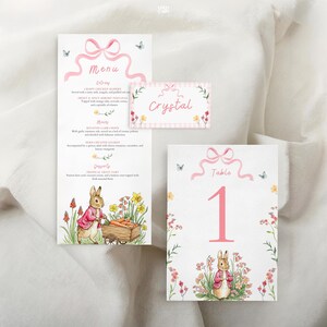 May include: A set of Easter-themed stationery with a menu, place card, and table number. The designs feature a pink bow, butterflies, and a watercolor illustration of a rabbit pushing a cart of carrots. The menu includes the word "Menu".