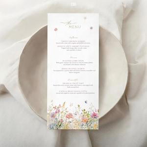 Peut inclure: Une carte de menu verticale avec des illustrations florales et le texte "The Menu". Le menu répertorie les entrées, les plats principaux et les desserts. La carte est blanche avec un motif floral à l'aquarelle en bas et en haut.