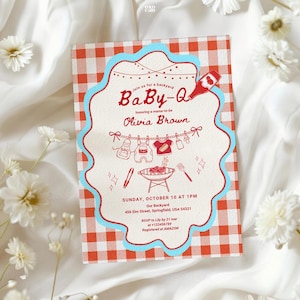 Baby-Q shower invitation with red gingham border and blue scalloped edge, displayed on white fabric with daisy flowers. Features string lights, clothesline with baby items, and BBQ grill illustration. Invites guests to honor Olivia Brown on Sunday October 10 at 1PM, 456 Elm Street Springfield. RSVP to Lily by March 21. Registry at Amazon.