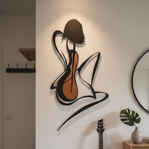 May include: A modern interior featuring a black electric guitar leaning against a white wall. A large, abstract metal wall art piece depicts a figure with a guitar. A round mirror and wooden console table complete the scene.