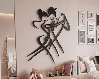May include: A black wall art piece featuring a stylized silhouette of two dancers in a tango pose. The design consists of fluid, continuous lines depicting a person with a bun hairstyle and a person wearing a hat, engaged in a dance movement.