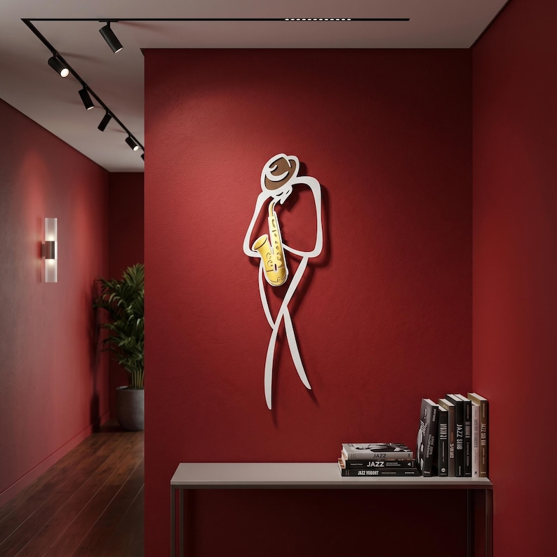 May include: A wall-mounted metal art piece depicting a stylized figure wearing a hat and playing a yellow saxophone. The sculpture features clean, white outlines forming the silhouette of a musician, with a distinct yellow instrument accent.