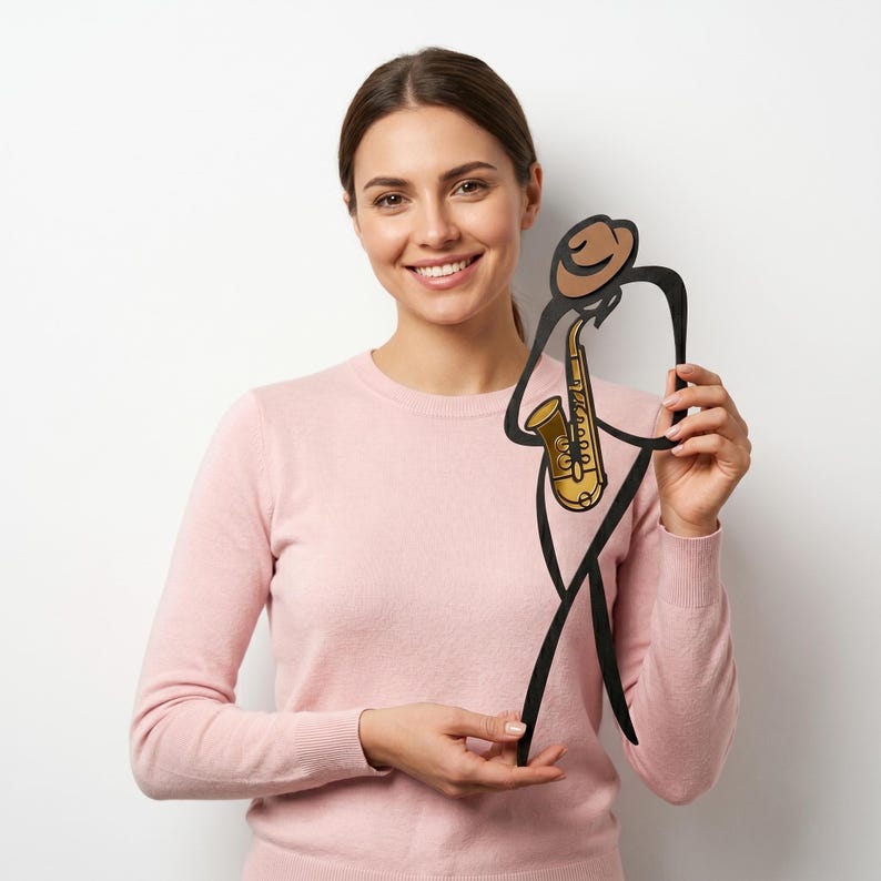 May include: A black metal wall art piece depicting a stylized figure wearing a brown hat and playing a gold-colored saxophone. The design features clean, minimalist lines that form the silhouette of a musician, with the instrument as a focal point.