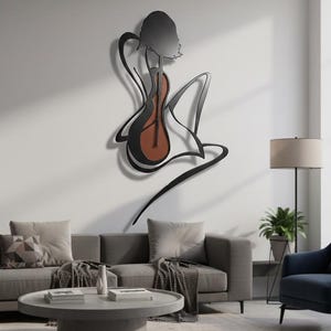May include: A black metal wall art piece depicting a figure playing a guitar. The guitar has a brown body. The art is mounted on a white wall above a gray sofa and coffee table, creating a modern aesthetic.