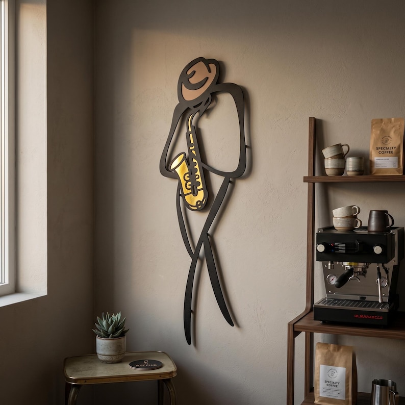 May include: A black metal wall art piece depicting a stylized figure wearing a hat and playing a gold-colored saxophone. The minimalist silhouette features clean, continuous lines that form the shape of a musician standing in a relaxed posture.