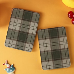 Puede incluir: Dos objetos rectangulares con un patrón de cuadros verdes, grises y blancos. Se encuentran sobre un fondo amarillo brillante, junto con una bola azul, un limón y cerezas. También hay una pequeña figura de conejo.