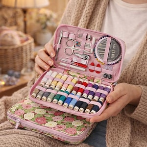 Pu&ograve; includere: Un kit da cucito rosa con un motivo floreale. Il kit aperto rivela rocchetti di filo colorato, aghi, forbici e altri elementi essenziali per cucire. Il kit &egrave; tenuto aperto, mostrando il suo contenuto.