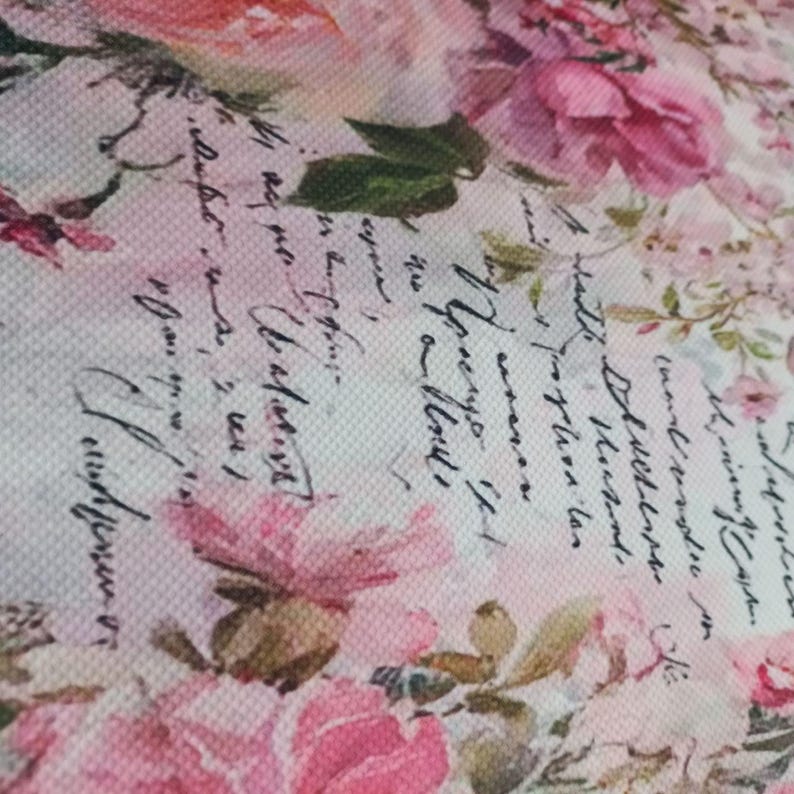 May include: A textured fabric featuring a floral pattern with various shades of pink roses and green leaves, overlaid with black cursive script text that appears as handwritten letters or vintage correspondence across the surface of the material.