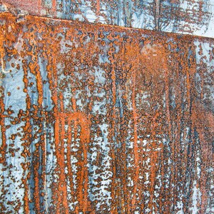 May include: Close-up of a rusty metal surface with a blue and orange color scheme. The surface has a textured, weathered look, with streaks of rust and blue paint.