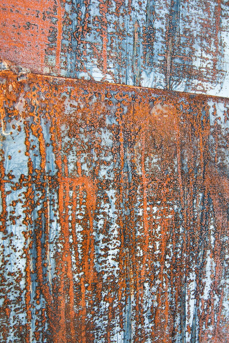 May include: Close-up of a rusty metal surface with a blue and orange color scheme. The surface has a textured, weathered look, with streaks of rust and blue paint.