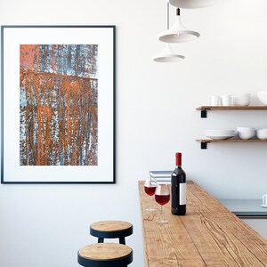 May include: A rustic wooden countertop with two bar stools, two glasses of red wine, and a bottle of wine. The countertop is in front of a white wall with a framed abstract painting and two wooden shelves with white dishes.