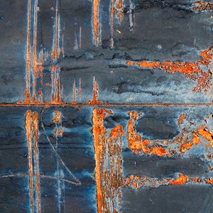 May include: Close-up of a rusty metal surface with streaks of orange and blue paint. The metal has a textured, worn look.