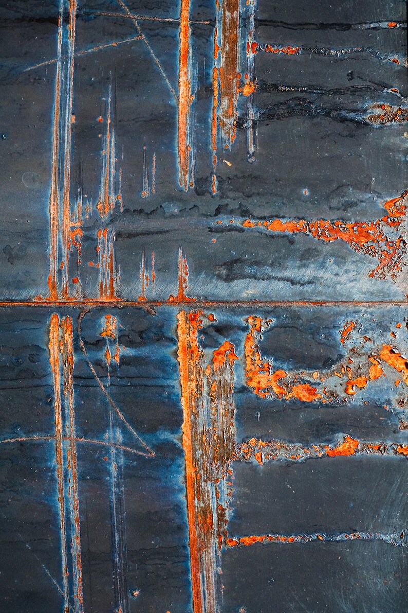 May include: Close-up of a rusty metal surface with streaks of orange and blue paint. The metal has a textured, worn look.