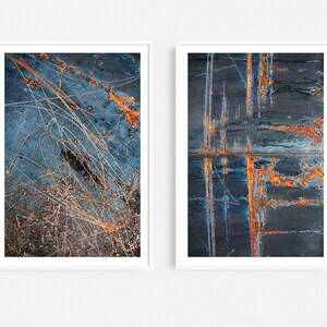 May include: Two abstract art prints featuring close-up images of rusty metal surfaces with blue, orange, and white tones.