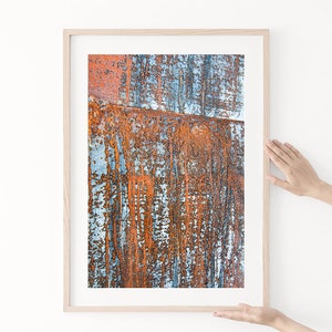 May include: A framed abstract print featuring a close-up of a rusty metal surface with blue and orange hues.