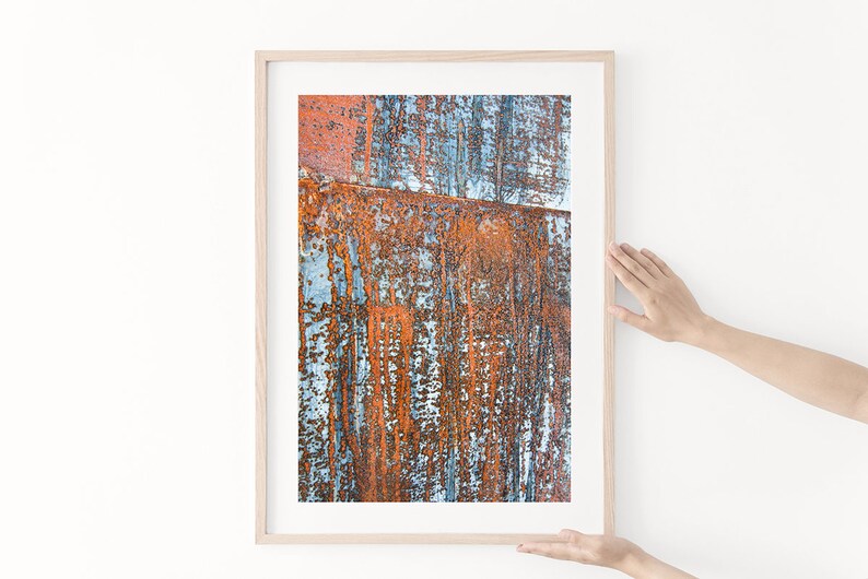 May include: A framed abstract print featuring a close-up of a rusty metal surface with blue and orange hues.