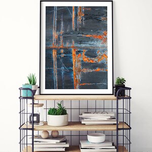 May include: A framed abstract art print featuring a close-up of a rusty metal surface with shades of blue, orange, and black.