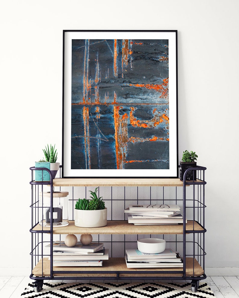 May include: A framed abstract art print featuring a close-up of a rusty metal surface with shades of blue, orange, and black.