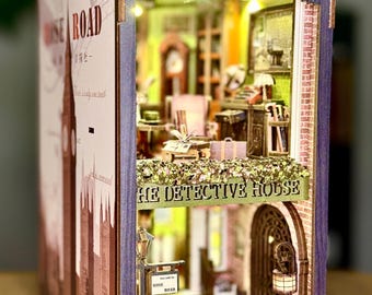 May include: A wooden book nook diorama titled The Detective House featuring a two-story interior with miniature furniture, a brick wall pattern, and a street scene with a fire hydrant, a lamp post, and yellow caution tape marked with the text KEEP OUT.