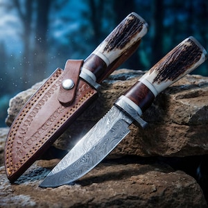 Peut inclure: Un couteau de chasse avec une lame en acier à motifs et un manche en bois et en os. Le couteau est accompagné d'un étui en cuir marron. Le couteau et l'étui reposent sur une roche.