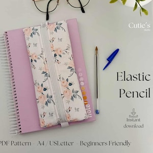 Pode incluir: Um estojo floral com zíper, sobre um caderno rosa. Uma caneta e uma tampa de caneta azul estão ao lado do caderno. O texto "Elastic Pencil" e "Instant download" são visíveis.