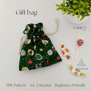 Pode incluir: Uma sacola de presente verde com fecho de cordão, decorada com enfeites de Natal e estrelas. A sacola está ao lado de doces e um pirulito. O texto na imagem diz "Gift bag", "Cutie's store" e "Instant download".