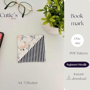 Könnte beinhalten: Quadratischer Lesezeichen mit floralem und gestreiftem Design. Das Lesezeichen ist diagonal geteilt, mit einem floralen Muster auf der einen Seite und marineblauen und weißen Streifen auf der anderen Seite. Der Text "Cutie's store" ist sichtbar.