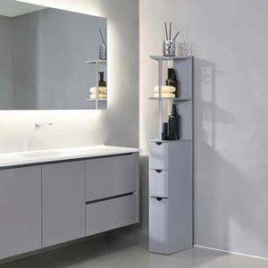 May include: A modern gray bathroom with a large mirror, a floating vanity, and a tall, narrow storage unit. The storage unit has open shelves and three drawers, holding toiletries and decorative items. The overall design is minimalist and functional.