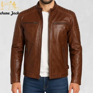 Könnte beinhalten: Braune Lederjacke mit Stehkragen und gesteppten Schulterdetails. Die Jacke hat zwei Brusttaschen mit Reißverschluss und zwei Seitentaschen. Der Markenname "Stitchure Jack" ist oben links sichtbar.