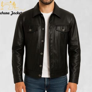 May include: Black leather jacket with a button-up front, two chest pockets, and a collared neckline. The jacket has a classic design and is worn over a white t-shirt and blue jeans. The text "Stitchure Jacket" is visible.
