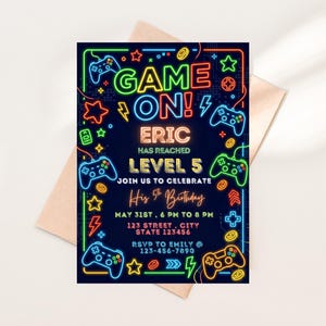 May include: A navy blue birthday invitation with neon-style graphics. The text reads "GAME ON!" with the name "ERIC" and "LEVEL 5". It includes party details and RSVP information, all in a vibrant, gamer-themed design.