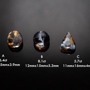 May include: Three blue and gold tiger's eye gemstones, labeled A, B, and C. Gemstone A is 6.4ct and measures 11mm x 15mm x 3.9mm. Gemstone B is 8.1ct and measures 12mm x 15mm x 5.3mm. Gemstone C is 5.7ct and measures 11mm x 16mm x 4mm.