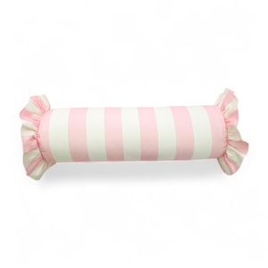 May include: A cylindrical decorative pillow with pink and white vertical stripes. The ends of the pillow have ruffled pink fabric, giving it a candy-like appearance. The pillow is designed for home decor.