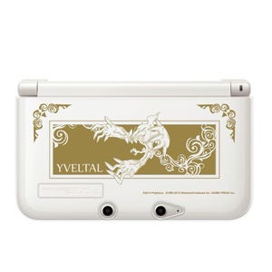 Könnte beinhalten: Weiße Nintendo 3DS XL Handheld-Spielkonsole mit goldenem Yveltal-Design. Das Design beinhaltet das Wort "Yveltal" und dekorative Wirbel. Die Konsole hat zwei schwarze runde Knöpfe und einen silbernen Regler.