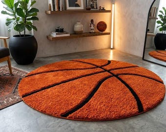 May include: Circular orange rug with a basketball design, featuring black lines representing the ball's seams. The rug is made of a soft material and is placed on a concrete floor. The rug is a decorative item for a living room or bedroom, approximately 180 cm in diameter.