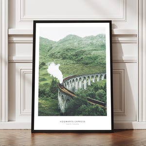 Pu&ograve; includere: Una stampa incorniciata raffigurante l'Hogwarts Express che attraversa un viadotto in pietra. L'immagine mostra un treno a vapore sullo sfondo di verdi colline e un cielo nuvoloso. La stampa &egrave; esposta su un pavimento in legno.
