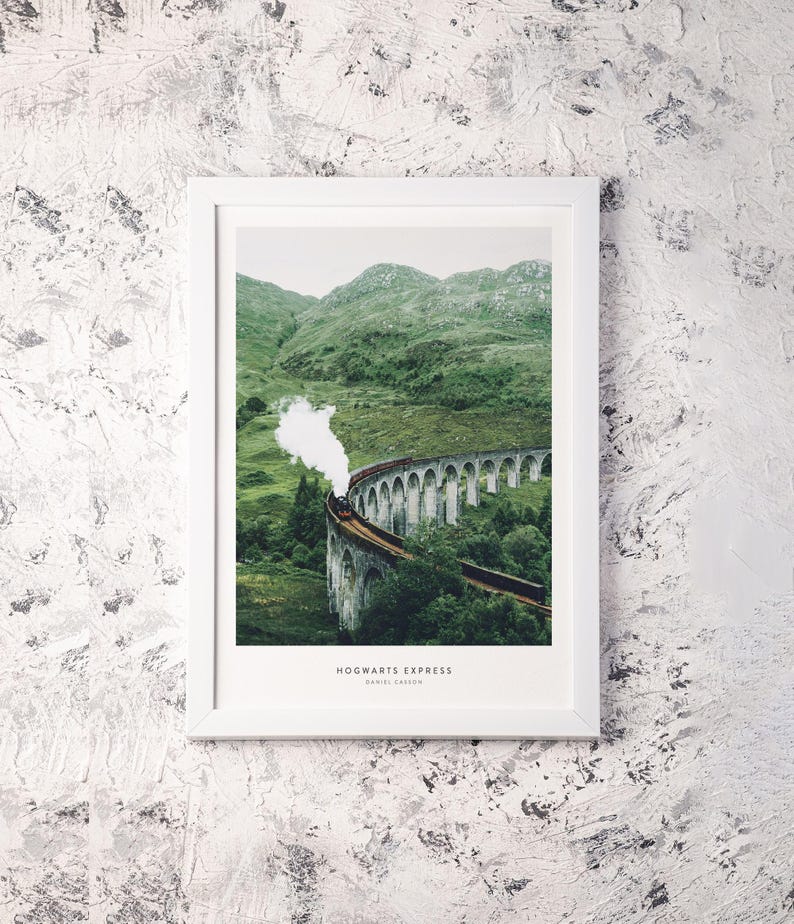 Pu&ograve; includere: Una stampa incorniciata del treno Hogwarts Express che attraversa un ponte di pietra in una verdeggiante valle. Il treno emette un pennacchio di vapore bianco. La stampa &egrave; in una cornice bianca ed &egrave; montata su una parete bianca strutturata. Il testo "HOGWARTS EXPRESS" e "DANIEL CARSON" &egrave; in basso.