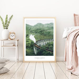 Pu&ograve; includere: Una stampa incorniciata del treno Hogwarts Express che attraversa il viadotto di Glenfinnan in Scozia. L'immagine mostra un treno a vapore su un ponte di pietra circondato da verdi colline. Il testo "Hogwarts Express" &egrave; in basso.