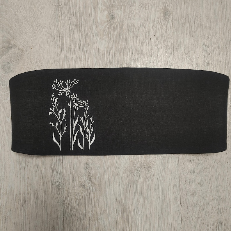 May include: A white ceramic mug with a black handle and the text "But First, Coffee" in a bold, black font. The mug is set against a neutral background, highlighting its simple design.