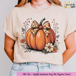 May include: A beige t-shirt featuring a large orange pumpkin with a checkered bow, surrounded by floral accents. The design is a digital download, as indicated by the text at the bottom of the image.